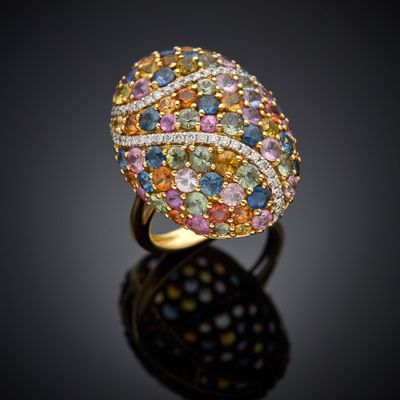 un gros plan d'une bague ornée de pierres multicolores sur un fond noir