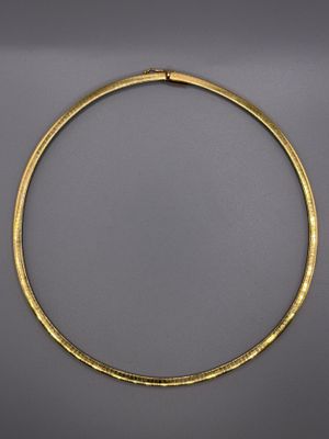 un collier en or au motif incurvé sur fond gris