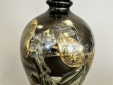 a black and gold vase sitting on a white surface