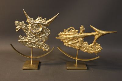 pair of gold metal sculptures of a dragon and a ship on a stand