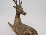 sculpture en bronze représentant un cerf couché sur une surface blanche