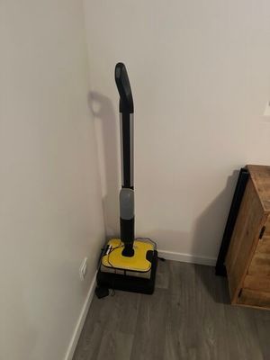 un aspirateur dans un coin de la pièce, à côté d'une commode