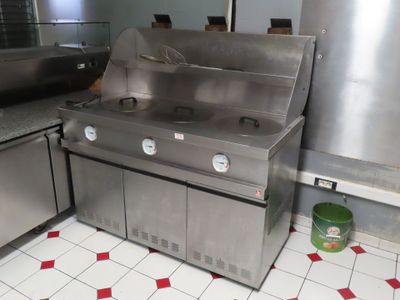 une cuisinière en acier inoxydable dans une cuisine au sol carrelé de rouge et de blanc