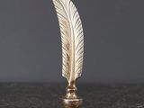 un objet en forme de plume dorée posé sur une table