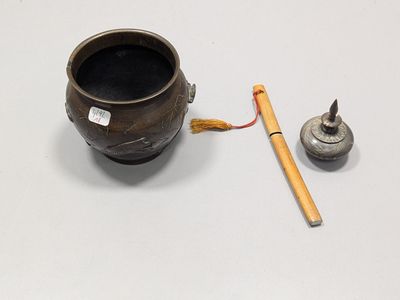 un petit récipient en métal avec un bâton en bois à côté