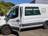 La camionnette blanche est garée sur le parking, la portière ouverte.