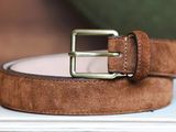 a brown belt with a metal buckle on a white table