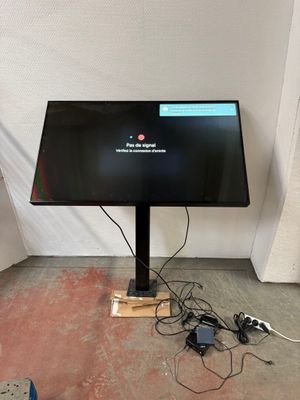 un écran d'ordinateur posé sur un support dans une pièce
