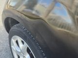 a close up of a car ' s front tire with a reflection of a building in the background