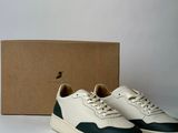the white and green sneakers are next to a cardboard box