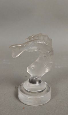 un poisson en verre transparent posé sur un socle, sur une table