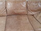 brown leather couch in a room with a white brick wall