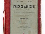 an old book with a red cover sitting on top of a white surface
