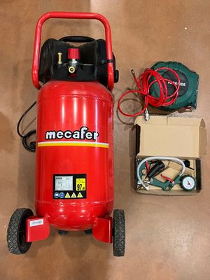 a red air compressor sitting on the floor next to a box of wires