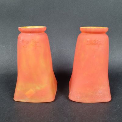 une paire de vases orange posés sur une surface noire, avec un fond noir