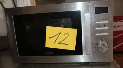 un micro-ondes posé sur une table, sur laquelle est collé un autocollant jaune