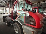 a red tractor that is parked inside of a building