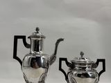 two silver teapots and a silver teapot on a white surface