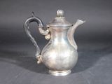 a silver tea pot with a handle on a table