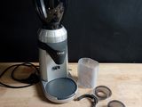 a coffee grinder sitting on a table next to a measuring cup