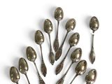 six silver spoons are arranged in a circle on a white surface
