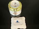 a small white plate with a yellow and blue lid next to a small white plate with a yellow and blue lid on a black surface