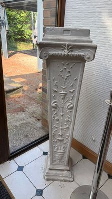 a white pedestal in the middle of a tiled floor