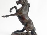 statue of a horse standing on its hind legs on a wooden base