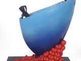 a sculpture of a blue bowl with red balls on it