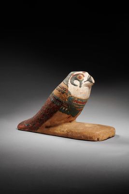an egyptian figurine of a bird on a wooden base