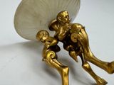 a gold figurine of a man and a woman holding an umbrella