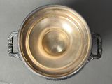a silver bowl with a handle on a table