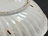 a white bowl with a brown rim sitting on a black surface