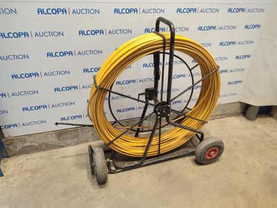 a cart with a yellow hose on it in front of a wall