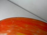 an orange and yellow bowl sitting on a white surface