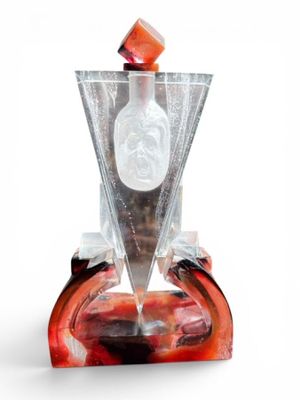a glass vase with a bottle on top of it