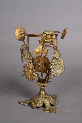 a gold vase with flowers and leaves on it