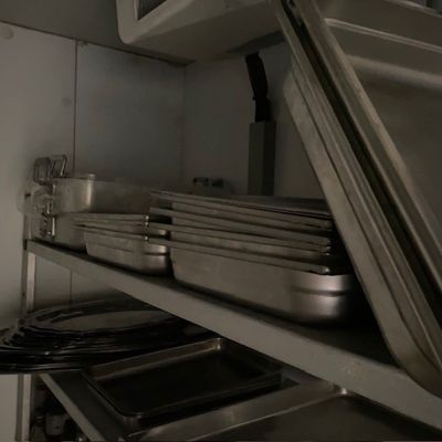 une pile de casseroles et de poêles posée sur une étagère dans une cuisine