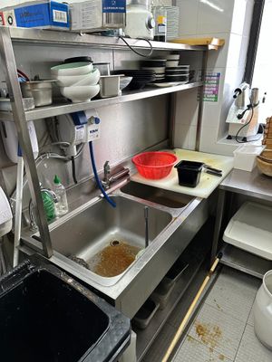 stainless steel shelvings in a kitchen with a sink and a trash can