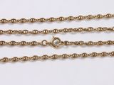 a close up of three gold chains on a white surface