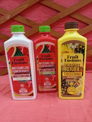 trois bouteilles d'eau aromatisée aux fruits (pastèque, citron et grenade) posées sur une nappe rose