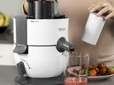 someone is pouring strawberries into a blender with a glass of juice