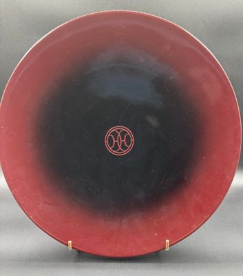 a close up of a red and black plate on a stand