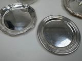 four silver plates on a white table with one silver plate in the middle