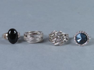 Quatre bagues différentes sont présentées sur une table avec un fond gris.