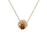 un collier en or orné d'une coccinelle rouge et blanche