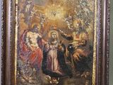 un vieux tableau représentant la Vierge à l'Enfant entourée d'anges, dans un cadre en bois