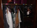 a wooden cabinet with clothes hanging on it in a room