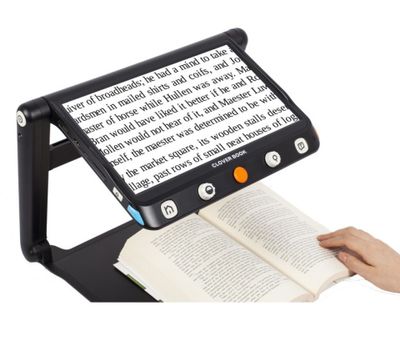 une personne en train de lire un livre sur lequel est posée une lampe loupe