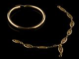 an image of a gold necklace and bracelet on a black background